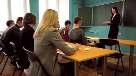 Profesor-de-la-mujer-hablando-con-los-estudiantes-durante-una-clase-en-aula