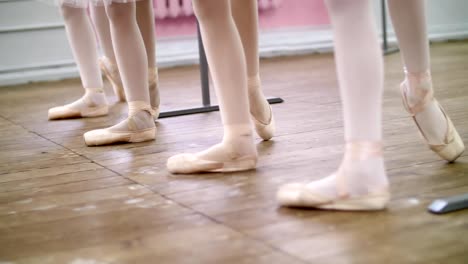 in-ballet-hall,-Young-ballerinas-perform-battement-tendue-back-in-pointe-shoes,-close-up