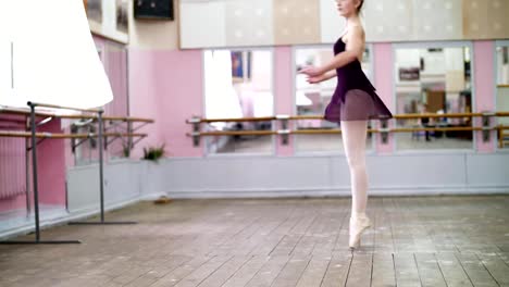 in-dancing-hall,-Young-ballerina-in-black-leotard-performs-tour-chaines,-She-moving-through-the-ballet-class-elegantly