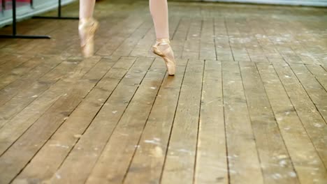 cerca,-en-el-salón-de-baile,-bailarina-realizar-paso-pointe,-ella-está-de-pie-en-los-pies-en-los-zapatos-del-pointe-con-elegancia,-en-un-viejo-piso-de-madera,-en-clase-de-ballet