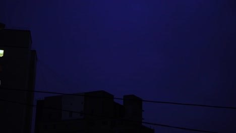 Relámpago-en-el-cielo-nocturno-de-la-ciudad,-un-brillante-destello-de-luz-en-las-nubes-en-la-lluvia,-una-tormenta-eléctrica