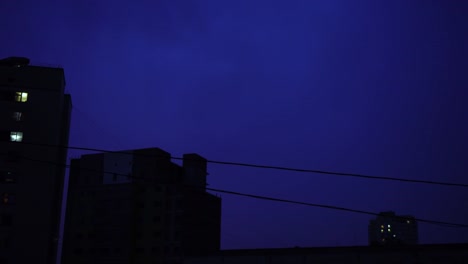 Relámpago-en-el-cielo-nocturno-de-la-ciudad,-un-brillante-destello-de-luz-en-las-nubes-en-la-lluvia,-una-tormenta-eléctrica