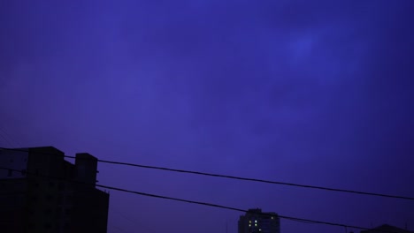 Relámpago-en-el-cielo-nocturno-de-la-ciudad,-un-brillante-destello-de-luz-en-las-nubes-en-la-lluvia,-una-tormenta-eléctrica