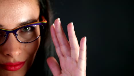 portrait-of-a-sexy-brunette-woman-with-red-lips-who-eroticly-and-playfully-tries-on-stylish-glasses,-spectacles-and-looking-sexually-at-camera-in-studio.-dark-gray-background