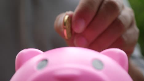 Hand,-setzen-Münzen-in-einem-Rosa-Sparschwein,-sparen-Geld-Konzept