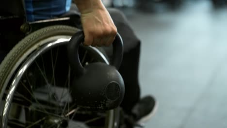 Hombre-en-silla-de-ruedas-haciendo-filas-ejercicios-con-Kettlebell