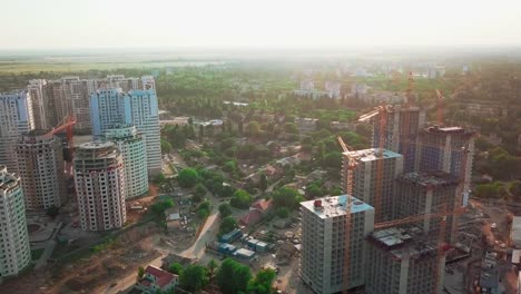 Aerial-drone-shot.-Construction-of-high-rise-buildings-in-the-developing-area-of-a-large-city.-Sunset-shot.-Construction-sites,-houses-handed-over,-construction-cranes-and-many-houses-under-construction.-wide-shot