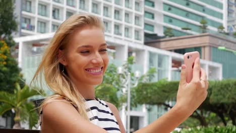 Hermoso-joven-delgada-a-mujer-con-el-pelo-largo-Rubio-en-vestido-blanco-y-negro-que-hace-selfie-en-teléfono-móvil-sobre-el-fondo-del-parque.