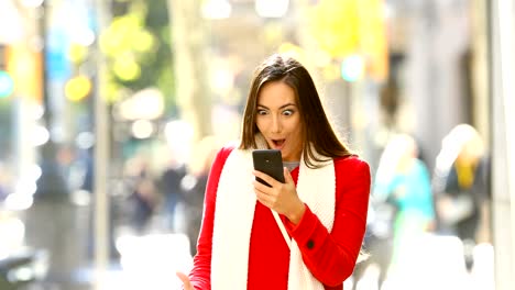 Shocked-woman-reading-online-news-in-the-street