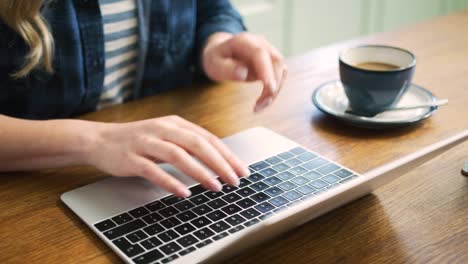 Frau-auf-Laptop-tippen-und-tranken-Kaffee-am-Tisch