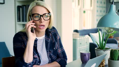 Attractive-Blond-Businesswoman-Talking-On-Smart-Phone-In-Home-Office