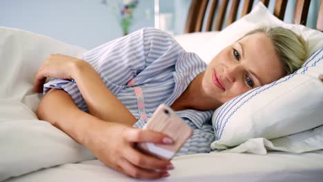 Beautiful-Blond-Woman-Checking-Her-Smart-Phone-After-Waking-Up