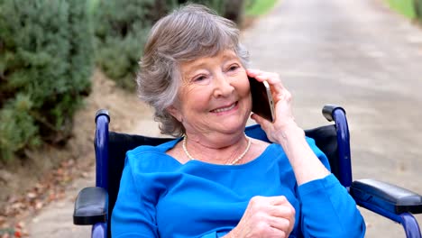 Senior-woman-talking-on-mobile-phone-on-wheelchair-4k