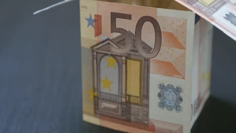 Abstract-house-made-of-Euro-paper-money-of-50-value-bills-close-up-4K-2160p-30fps-UltraHD-video---Zooming-to-fifty-Euros-banknotes-made-house-4K-3840X2160-UHD-footage