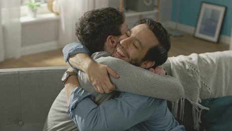 Slow-Motion-für-ein-süßes-männliche-Gay-paar-beisammen-sitzen-auf-einem-Sofa-zu-Hause.-Freunde-sind-Hugging-und-umarmen-einander.-Sie-sind-glücklich-und-Lächeln.-Sie-sind-lässig-gekleidet-und-Zimmer-ist-Modern-eingerichtet.