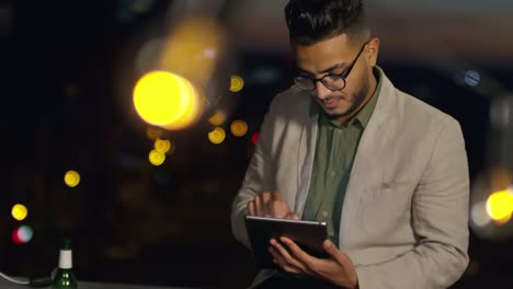 Joven-árabe-usando-tableta-en-la-noche-en-la-azotea