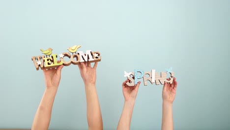 Ostern-Konzept.-Frühlings--und-willkommen.-Die-Hände-von-Kindern-halten-ein-Holzdekor-auf-einem-blassen-blauen-Hintergrund,-dann-breitete-es-auseinander