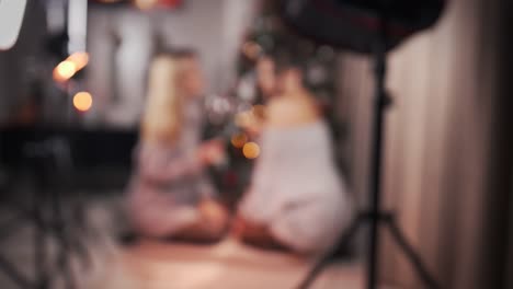 Defocus-Two-multiracial-girlfriends,-with-large-glasses-and-wine-in-their-hands.-During-a-studio-photo-shoot-or-at-home.-Asian-and-Caucasian-women.-Concept-of-female-friendship,-lgbt-and-celebration-of-Christmas.-4k,-slow-motion