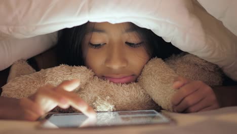 Little-girl-using-tablet-in-the-bedroom.