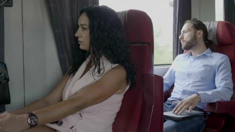 Business-man-and-elegant-passenger-woman-traveling-on-train-man-using-digital-smartphone-relaxing-during-journey