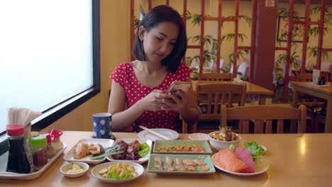 Young-Asian-Woman-Taking-Photo-and-Selfie-with-Salmon,-Chicken,-Sashimi-Japanese-Food.