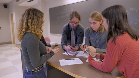 Professor-und-drei-Studenten-nehmen-alle-heraus-und-beginnen-mit-dem-Handy