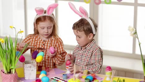 Happy-children-wearing-bunny-ears-painting-eggs-on-Easter-day.-Little-girls-preparing-for-the-Easter.