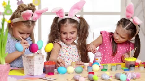 Happy-children-wearing-bunny-ears-painting-eggs-on-Easter-day.