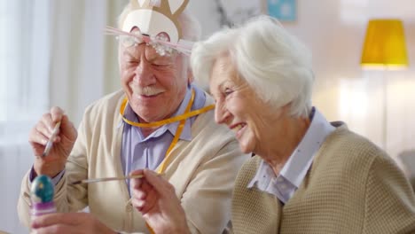 Elderly-Couple-Painting-Eggs-and-Smiling