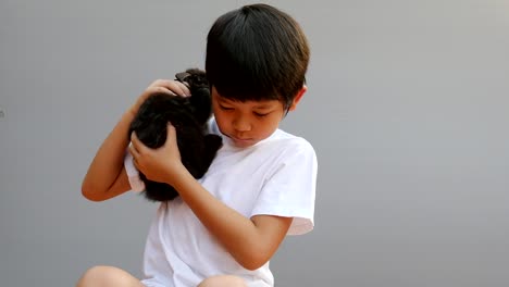 Young-Asian-kid-is-playing-with-lovely-black-rabbit