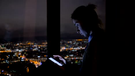 Mujer-usando-un-smartphone-negro-vertical-por-la-noche