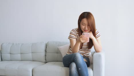 Asian-woman-using-cellphone-in-living-room