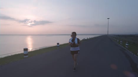 Asiatische-Frauen-joggen-in-der-Straße-am-frühen-Morgen-Sonnenlicht-am-Wasserspeicher-Pa-Sak-Jolasid-Dam.-Konzept-des-Gewichtsverlustes-mit-Bewegung-für-die-Gesundheit.-zeitlupe