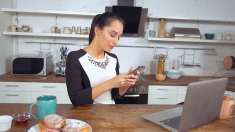 Hermosa-dama-bonita-sosteniendo-smartphone-en-la-cocina