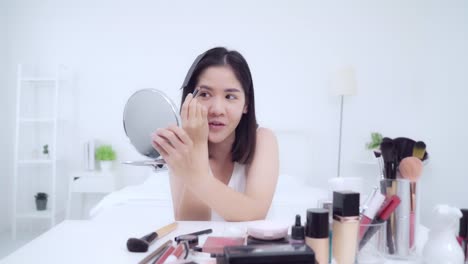 La-bloguera-de-belleza-presenta-cosméticos-de-belleza-sentados-en-la-cámara-frontal-para-grabar-vídeo.-Feliz-hermosa-joven-asiática-mujer-utilizar-cosméticos-revisión-maquillaje-tutorial-transmisión-de-vídeo-en-vivo-a-la-red-social.