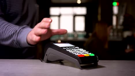 Close-up-shot-of-woman-using-terminal-and-credit-card-performs-contactless-paypass-payment.