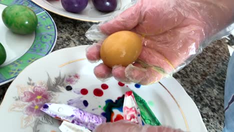 A-woman-in-gloves-paints-eggs