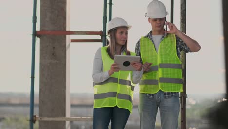 The-controller-is-a-man-of-a-building-under-construction-talking-on-the-phone-with-management-and-has-discussed-with-the-engineer-and-architect-woman-construction-progress