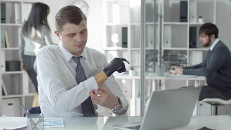 Businessman-Working-on-Laptop-and-Taking-Off-Prosthetic-Hand