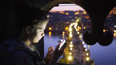 Girl-enjoying-aerial-view-Charles-bridge-through-the-window-at-twilight