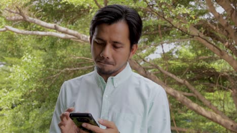 Hombre-asiático-disfrutando-del-éxito-mientras-se-utiliza-Smartphone