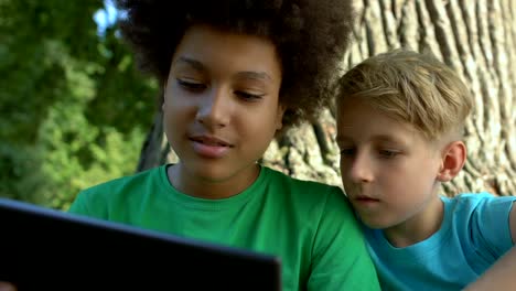 Male-friends-scrolling-tablet-application-sitting-outdoors-together,-technology