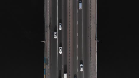 Bridge-highway-dark-water-cars-traffic-aerial-top-view-tracking-shot