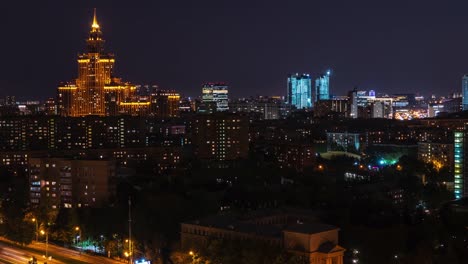 Timelapse-architecture-night-city-on-dark-sky-landscape.-Night-illumination-in-modern-city.-Moon-moving-in-cloudy-sky-over-dark-city.-Night-city-landscape-from-drone