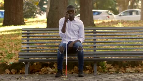 Blind-black-young-man-sitting-on-bench-in-the-park.blindness,-autonomy