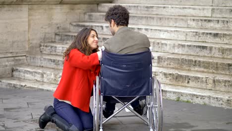 Young-woman-comforting-her-sad-boyfriend-on-wheelchair.Handicap,love,support