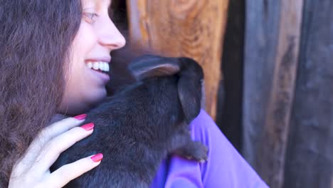 Konzept-niedliche-schöne-Tiere.-Hase-in-den-Händen-eines-Teenagers.-Viehzucht-und-Landwirtschaft,-Kaninchenfarm,-Kinder-und-Tiere,-Sommerferien.-Kontakt-mit-Hasen-und-Haustieren.-Nahaufnahme.