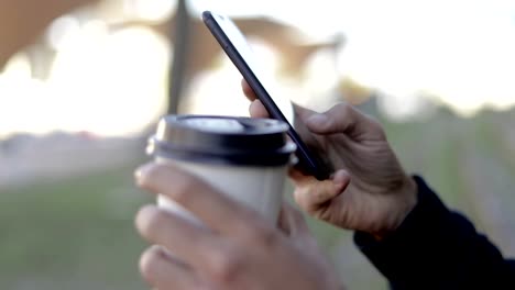 Recortado-tiro-de-hombre-con-café-para-ir-usando-el-teléfono-inteligente