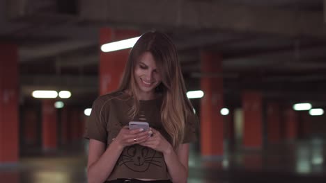 Relaxed-young-woman-using-smartphone-surfing-social-media,-checking-news,-playing-mobile-games-or-texting-messages-standing-in-the-supermarket-parking-lot.