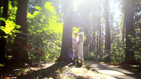 Paar-in-der-Liebe-im-Wald-Tilt-Shift.-Mann-am-Baumstamm-gelehnt-hält-umfassende-schöne-blonde-Frau-in-seinen-Händen,-küsste-ihre-Stirn-und-Nase.-Süße-romantische-Zärtlichkeit-Verständnis-Konzept